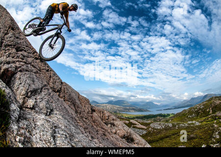 Ein Mann fährt mit einem Mountainbike-Rad eine Felsplatte auf der Halbinsel Applecross im Nordwesten der schottischen Highlands hinunter. Stockfoto