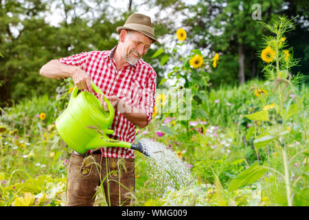 Porträt der schönen bayerischen Mann in den Garten und Bewässerung der Blumen Stockfoto