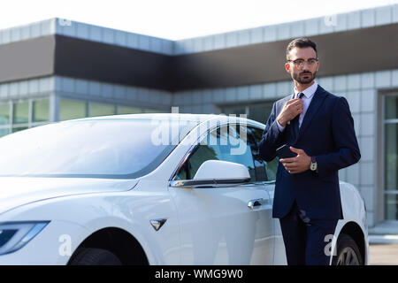 Unternehmer stehen in der Nähe von white Auto am Morgen Stockfoto