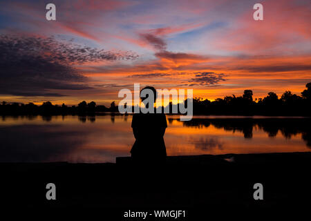 Eine dramatische, Orange Sonnenaufgang über Srah Srang mit einer Frau in Angkor in Siem Reap, Kambodscha. Stockfoto