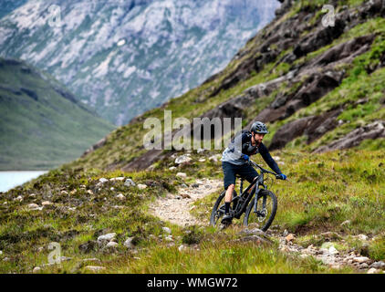 Ein Mann reitet ein Mountainbike auf einem Trail zwischen Elgol und Sligachan auf die Isle of Skye an der Westküste von Schottland. Stockfoto