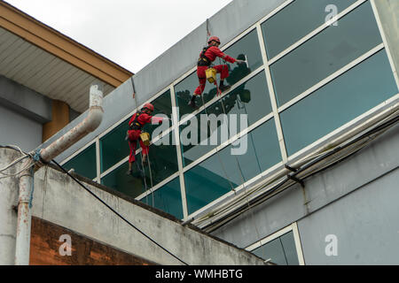DENPASAR/Bali, Indonesien - 26. AUGUST 2019: Hausmeister oder Reinigung Service waren die Reinigung der Fenster befindet sich auf der Höhe eines mit kompletten safet Gebäude Stockfoto