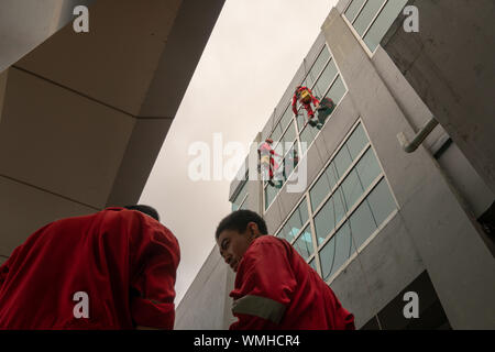 DENPASAR/Bali, Indonesien - 26. AUGUST 2019: Hausmeister oder Reinigung Service waren die Reinigung der Fenster befindet sich auf der Höhe eines mit kompletten safet Gebäude Stockfoto