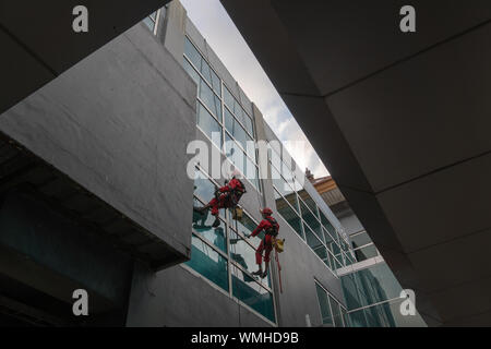 DENPASAR/Bali, Indonesien - 26. AUGUST 2019: Hausmeister oder Reinigung Service waren die Reinigung der Fenster befindet sich auf der Höhe eines mit kompletten safet Gebäude Stockfoto