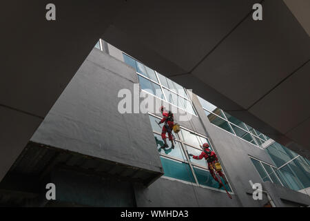 DENPASAR/Bali, Indonesien - 26. AUGUST 2019: Hausmeister oder Reinigung Service waren die Reinigung der Fenster befindet sich auf der Höhe eines mit kompletten safet Gebäude Stockfoto