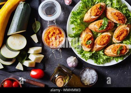 Getoastetes Brot Bruschetta mit Gemüsepüree, Püree, Kaviar von Zucchini, Tomaten, Karotten und Gewürze auf einem weißen Teller gekocht. Zutaten auf eine Co Stockfoto