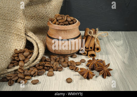 Kaffeebohnen überlaufen von einem kleinen Topf, würzige, Sternanis und Zimtstangen in einem rustikalen noch Leben auf einem Holztisch mit Platz kopieren Stockfoto