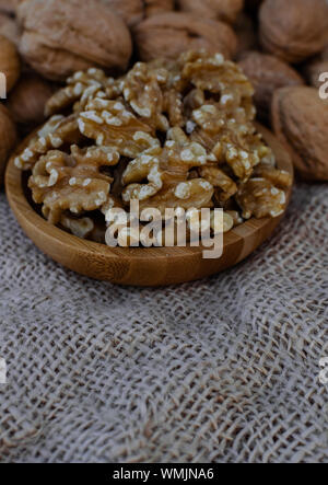 Walnüsse in Holz- runde Schale, Walnüsse mit Schale auf sack Oberfläche Stockfoto