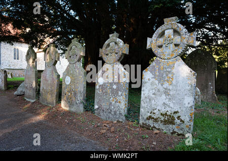 Reihe der Friedhof Grabsteine gekrönt mit einem keltischen Kreuz an der angelsächsischen Kirche von St Mary's, Breamore, Hampshire, England, Großbritannien Stockfoto