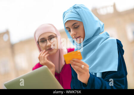 Muslimische Frau in Blau hijab Verarbeitung online Zahlung Stockfoto