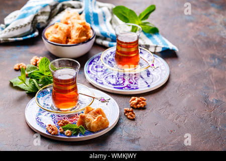 Im Nahen und Mittleren Osten oder arabischen Tee mit Minze in einem traditionellen Glas Schale und Türkische Süßigkeit Baklava. Ramadan Kareem. Eid Mubarak. Islamische Feiertage decorat Stockfoto