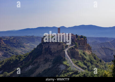 Am frühen Morgen Licht fangen die italienische Stadt von Bagnoregio, Viterbo Provinz. Auf der Tuff Felsvorsprung thront, blaue und dunstige Berge hinter gesehen werden kann. Stockfoto