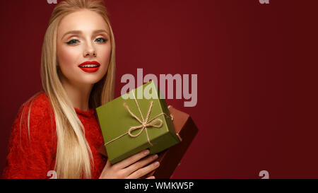 Schöne blonde Mädchen im Bild ist ein neues Jahr mit Boxen von Geschenken in den Händen. Schönheit Gesicht mit festlichen Make-up. Stockfoto