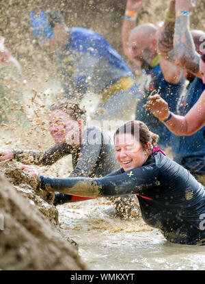 Konkurrenten verhandeln die 'Mud Mile' Hindernis im harten Mudder Ausdauer Event im Badminton Park, Gloucestershire, Großbritannien Stockfoto