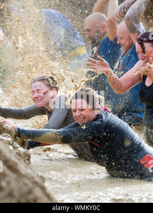 Konkurrenten verhandeln die 'Mud Mile' Hindernis im harten Mudder Ausdauer Event im Badminton Park, Gloucestershire, Großbritannien Stockfoto