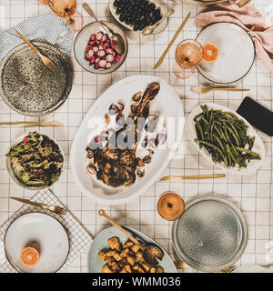 Familie, Freunde treffen zum Abendessen. Flachbild-lay von gebratene Lammschulter, Salate, gebackenem Gemüse, Snacks, Brot, Rose Wein und blühenden Mimosen Zweige o Stockfoto