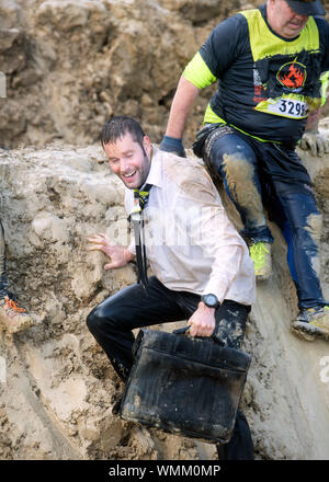 Konkurrenten verhandeln die 'Mud Mile' Hindernis im harten Mudder Ausdauer Event im Badminton Park, Gloucestershire, Großbritannien Stockfoto