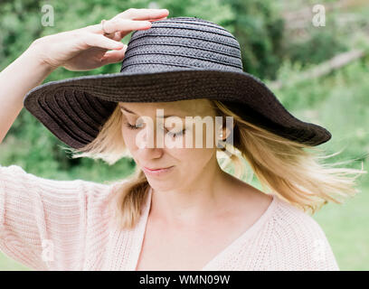 Frau, die Holding ihren Hut im Wind Stockfoto