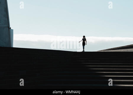 Silhouette einer Frau zu Fuß auf Treppen mit blauen Himmel im Hintergrund Stockfoto
