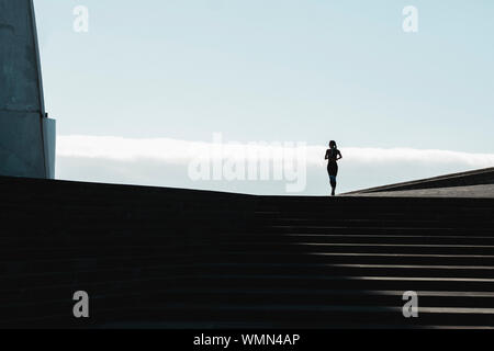 Silhouette einer Frau, die auf Treppen mit blauen Himmel im Hintergrund Stockfoto