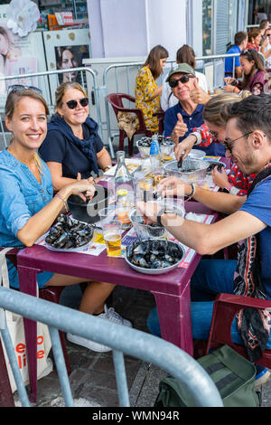 Lille, Frankreich - September 01,2019: Große Lille Braderie (Braderie de Lille). Glückliche Menschen essen traditionelles Gericht auf Lille Braderie, Muscheln und Pommes frites. Stockfoto