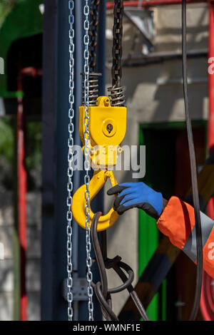 Gelbe Kranhaken und eine Kette heben Gewicht Stockfoto