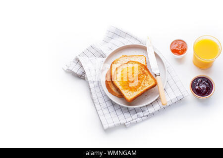 Morgen Toast mit Butter und Marmelade auf weißen Tisch mit Orangensaft serviert. Flatlay, Ansicht von oben Stockfoto