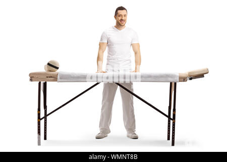 In voller Länge Porträt einer männlichen Masseur hinter einer professionellen Massage Bett auf weißem Hintergrund stehend Stockfoto