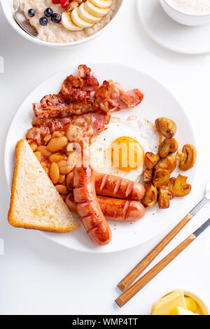 Klassische englische Frühstück mit gebratenem Speck, Pilze und Eier. Flatlay auf weißem Hintergrund Stockfoto