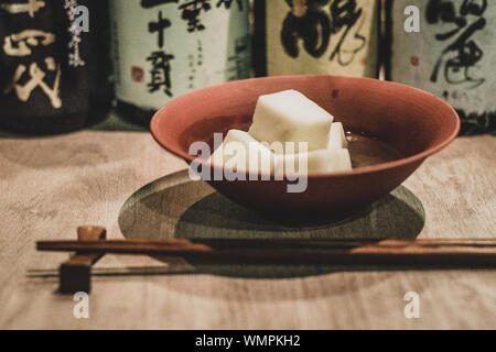 Japanische Fisch Kuchen Würfel oden angeordnet und in einem roten Schüssel in einem traditionellen japanischen Izakaya serviert. Stockfoto