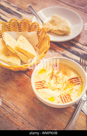 Hummus pürierte Kichererbsen, Tahini, Zitrone, Knoblauch beträufelt mit extra natives Öl mit Fladenbrot serviert. Stockfoto