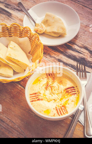 Hummus pürierte Kichererbsen, Tahini, Zitrone, Knoblauch beträufelt mit extra natives Öl mit Fladenbrot serviert. Stockfoto