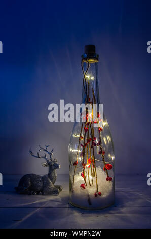 Weihnachten Flasche mit Lichtern auf weißem Hintergrund mit Rehen Stockfoto