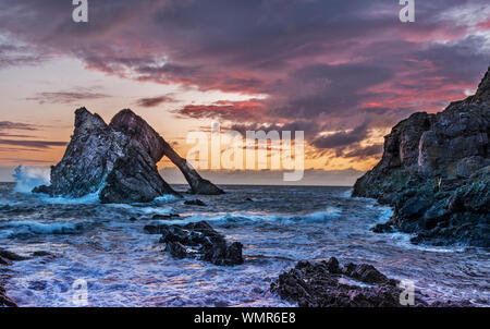 Bogen GEIGE ROCK PORTKNOCKIE Moray in Schottland Bunte sunrise mit STÜRMISCHEN MEER UND SPRAY AUF DEM ROCK Stockfoto