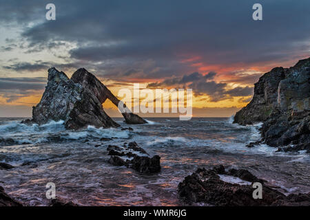 Bogen GEIGE ROCK PORTKNOCKIE Moray in Schottland Bunte sunrise mit stürmischer See, und die Wellen DIE FARBE AUS DEM HIMMEL widerspiegelt Stockfoto