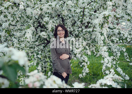 Eine junge schwangere Frau in einem Apple Orchard im Herzen von Warschau. Entspannen im Frühjahr in Polen Stockfoto