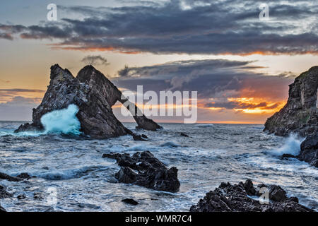 Bogen GEIGE ROCK PORTKNOCKIE Moray in Schottland Sonnenaufgang mit stürmischer See und beeindruckenden Wellen und Sprühen Stockfoto