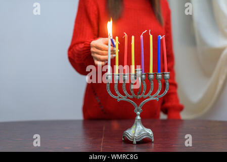 Jüdische Frau Beleuchtung Hanukkah Kerzen in einem MENORAH. Die Menschen feiern Chanukka durch Beleuchtung Kerzen auf der Menora, auch als Hanukiyah. Jede Nacht, eine weitere Kerze angezündet wird. Stockfoto