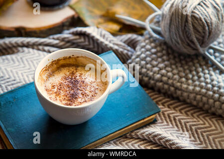 Herbst Kaffee Tasse mit Buch und Stricken wolle und Nadeln, gemütliche Herbst deco Konzept, Home Lifestyle warme Kaffeetasse im Herbst Saison Stockfoto
