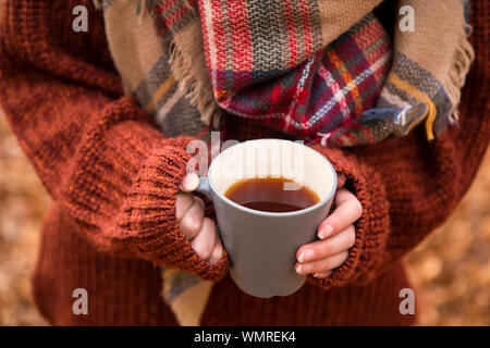 Herbst warme Tasse Tee, Frau mit Tasse Tee mit warmen gemütlichen Pulli und Schal, outdoor Herbst Konzept Tasse Tee Stockfoto