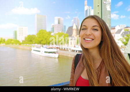 Stadt Tourismus Lifestyle in Deutschland. Lächelnd touristische Frau auf Frankfurt am Main Brücke mit Stadtbild. Stockfoto