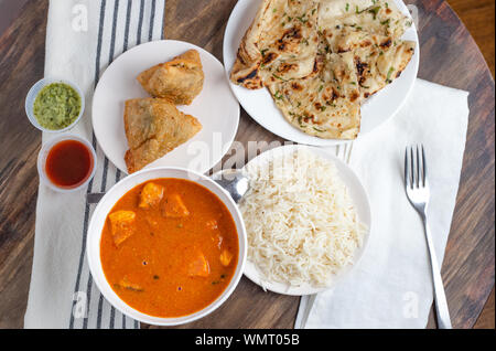 Indisches essen von Chicken Tikka Masala, Samosas und Knoblauch Naan Schuß von oben Stockfoto