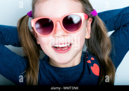 Freundlich lächelnde niedliche Kind mit Zähnen abgefallen - vorschüler Mädchen in der Sonnenbrille mit offenen Mund ohne Milch Zahn Stockfoto