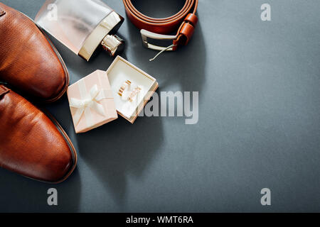 Für den Bräutigam Hochzeit Zubehör. Aus braunem Leder, Schuhe, Gürtel, Parfum, goldene Ringe. Männliche Mode Stockfoto