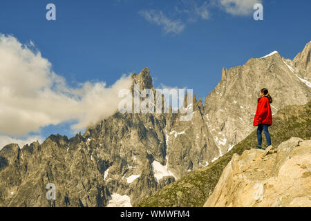 Junge Frau auf einem Felsen mit Blick auf das Mont Blanc Massiv mit der Aiguille Noire de Peuterey Berg, Courmayeur, Aostatal, Italien stehend Stockfoto