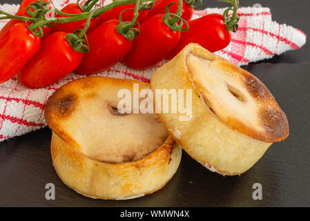 Zwei runde Scotch Kuchen frisch aus dem Ofen und serviert auf einem schwarzem Schiefer Servierteller und Cherry strauchtomaten an der Seite.. Stockfoto