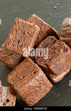 Kleines Quadrat Schneiden Chocolate Brownies al krümelig und auf einem schwarzen Schiefer Fach. Stockfoto