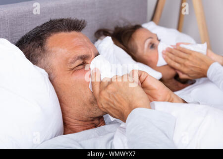 Sick Reifes Paar liegend auf Bett bläst Ihre Nase im Schlafzimmer Stockfoto