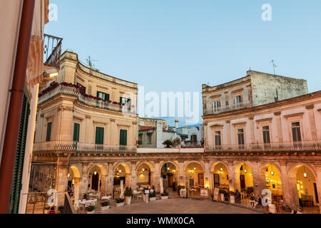 Italien, Apulien, Provinz Tarent, Martina Franca. 29. Mai 2019. Piazza Maria Immacolata, gewölbten Arkaden mit Cafés. Stockfoto