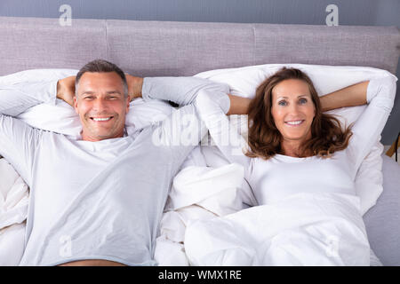 Glückliches Paar liegend auf Bett mit weißer Decke im Bett Zimmer Stockfoto